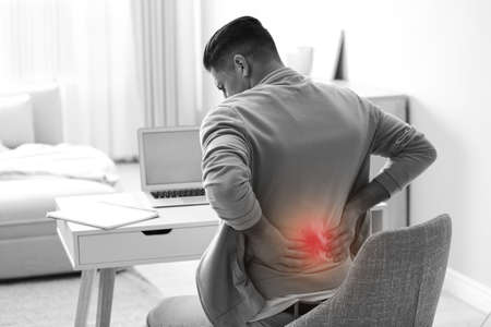 Man suffering from back pain at workplace. Bad posture problemの写真素材