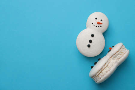 Beautiful snowman Christmas macarons on light blue background, flat lay. Space for textの写真素材