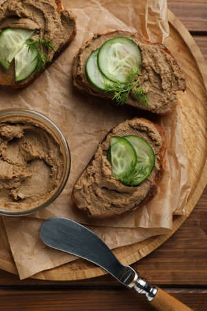 Slices of bread with delicious pate, cucumber and dill on wooden table, top view