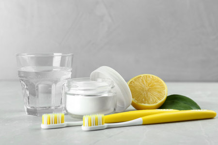 Toothbrushes, lemon and jar of baking soda on light gray tableの写真素材