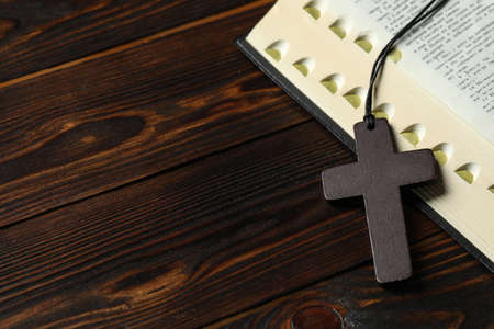 Wooden Christian cross and Bible on table, closeup. Space for textの写真素材
