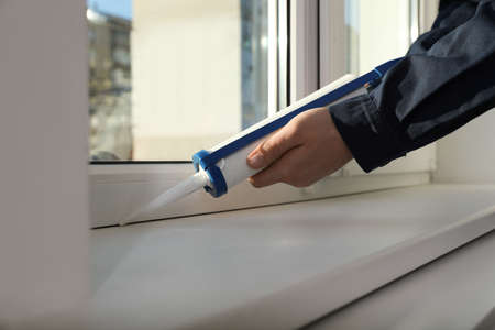 Construction worker sealing window with caulk, closeup
