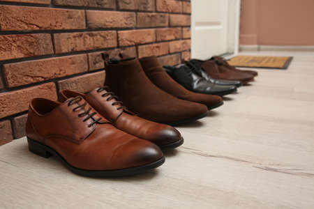 Different shoes near red brick wall in hallway