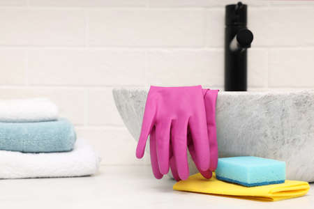 Sponge, rag and rubber gloves near sink in bathroom. Space for textの写真素材