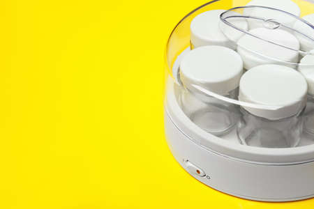Modern yogurt maker with empty jars on yellow background, closeup. Space for textの写真素材