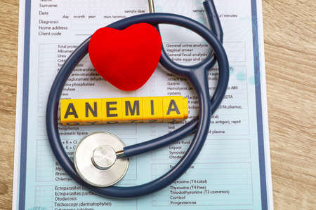 Word Anemia made with cubes, stethoscope, medical form and decorative heart on wooden table, above viewの写真素材