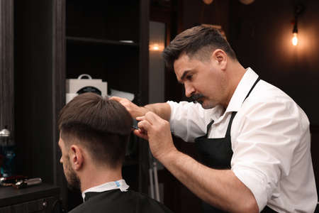 Professional hairdresser making stylish haircut in barbershopの写真素材