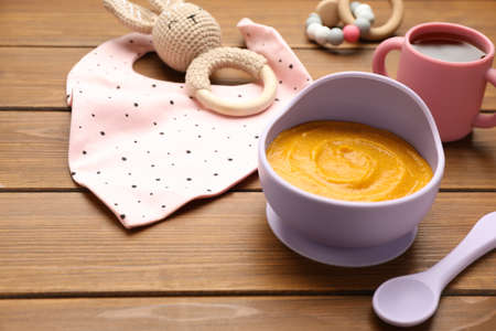 Plastic dishware with healthy baby food on wooden table. Space for textの写真素材