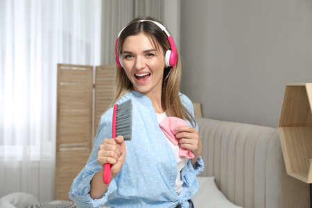 Woman in headphones with hairbrush singing at home