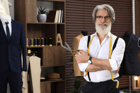 Professional tailor with measuring tape in workshop, space for text
