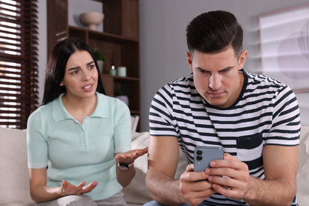 internet addiction. Man with smartphone ignoring his girlfriend in living room