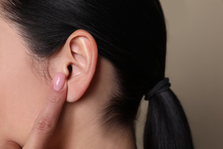 Woman pointing at her ear on gray background, closeupの写真素材