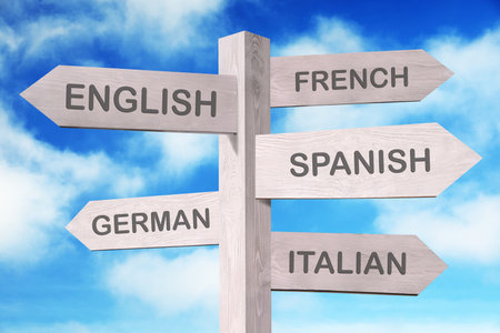 Wooden signpost with names of different languages against blue skyの写真素材