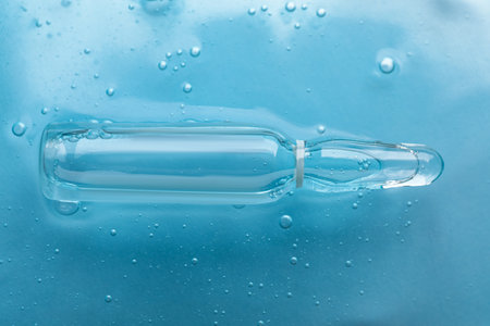 Pharmaceutical ampoule with medication in transparent gel on light blue background, closeupの写真素材