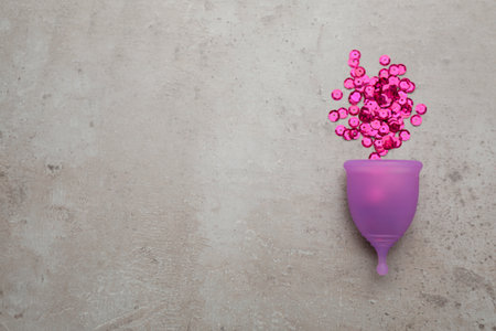 Menstrual cup and pink sequins on gray background, flat lay. Space for textの写真素材