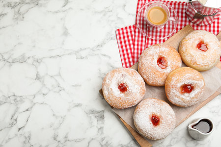 Delicious jam donuts served with coffee on white marble table, flat lay. Space for textの写真素材