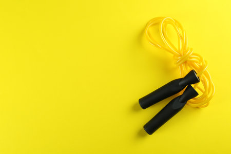 Skipping rope on yellow background, top view. Space for textの写真素材
