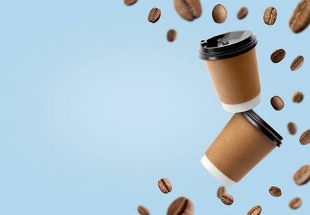 Coffee to go. Paper cups and roasted beans flying on light blue background, space for textの写真素材