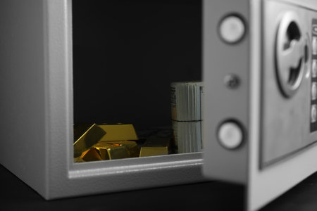 Open steel safe with money and gold bars on black table, closeupの写真素材
