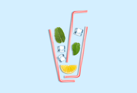 Creative lemonade layout with lemon slice, mint, ice cubes and straws on turquoise background, top...