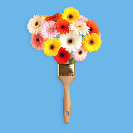 Creative design with paint brush and beautiful gerbera flowers on turquoise background. spring is...