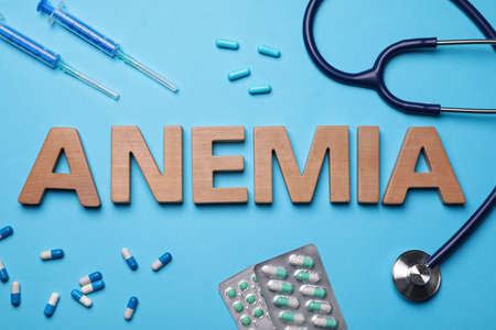Word Anemia, pills, syringes and stethoscope on light blue background, flat layの写真素材