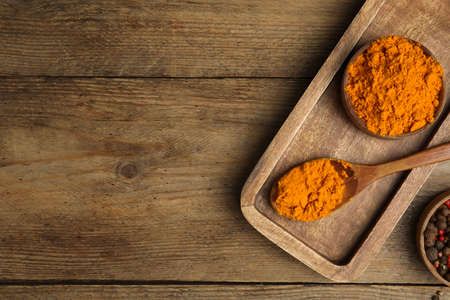 Saffron powder and peppercorns on wooden table, flat lay. Space for text