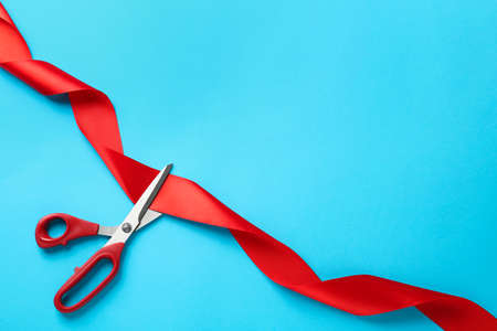 Red ribbon and scissors on light blue background, top view. Space for textの写真素材