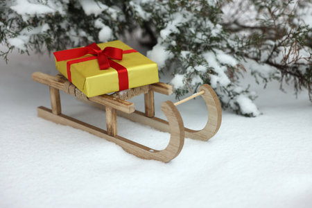 Wooden sleigh with gift box on snow outdoorsの写真素材