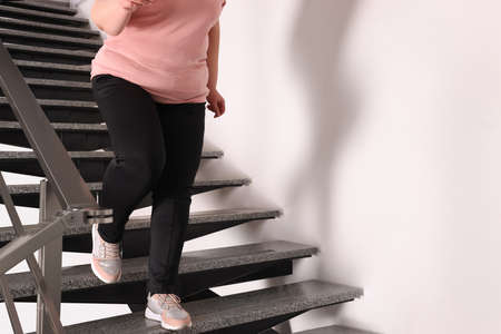 Overweight mature woman running downstairs indoors, closeup. Space for text