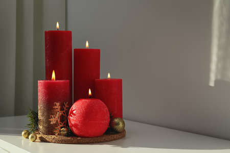 Burning candles with Christmas decor on white table. Space for text