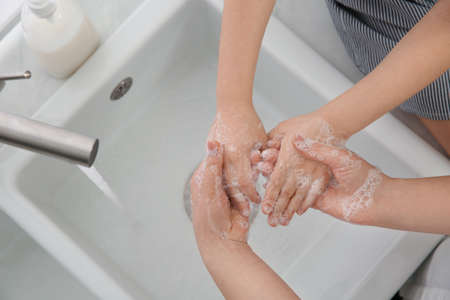 Mother and daughter washing hands with liquid soap together at home, closeupの写真素材