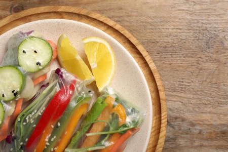 Delicious rolls wrapped in rice paper on wooden table, top view. Space for textの写真素材