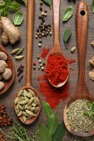 Different herbs and spices with spoons on wooden table, flat layの写真素材