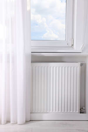 Modern radiator on wall under window indoors. central heating systemの写真素材