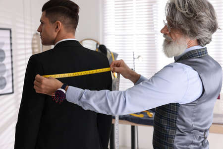 Professional tailor measuring client's back widthの写真素材