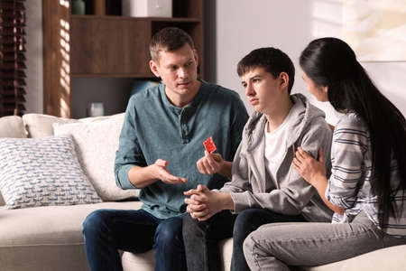Parents talking with their teenage son about contraception at home. sex education concept