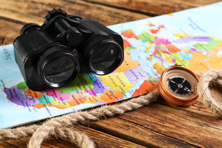 Modern binoculars, map, compass and rope on wooden tableの写真素材