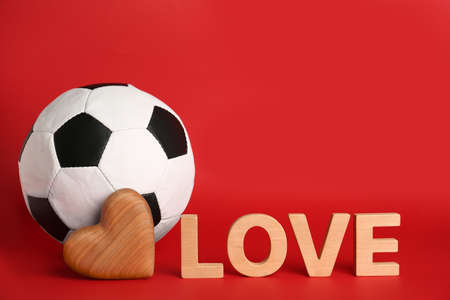 Soccer ball, word Love and heart on red background. Space for textの写真素材