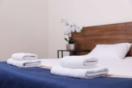 Clean folded towels on bed in hotel roomの写真素材