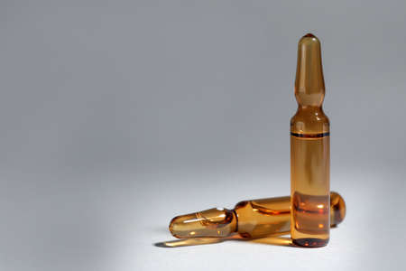 Brown pharmaceutical ampoules with medication on light background. Space for textの写真素材