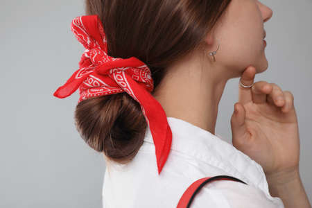 Young woman with stylish bandana on gray background, closeup
