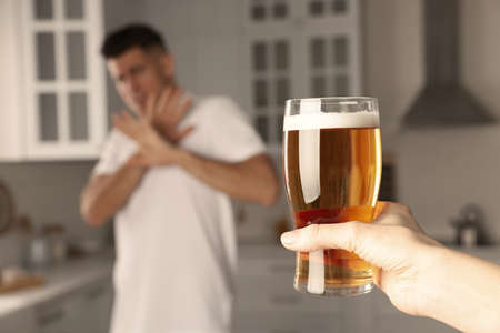 Man refusing to drink beer in kitchen, closeup. Alcohol treatment addictionの写真素材