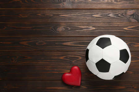 Soccer ball and heart on wooden background, flat lay. Space for textの写真素材
