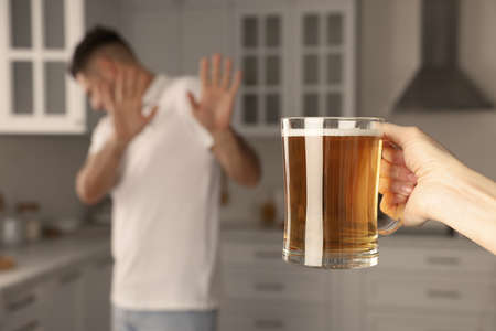 Man refusing to drink beer in kitchen, closeup. Alcohol treatment addictionの写真素材