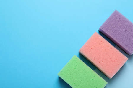 New sponges on light blue background, flat lay. Space for textの写真素材