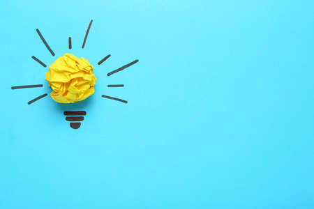 Creative composition with paper ball as lightbulb on light blue background, space for text. idea...