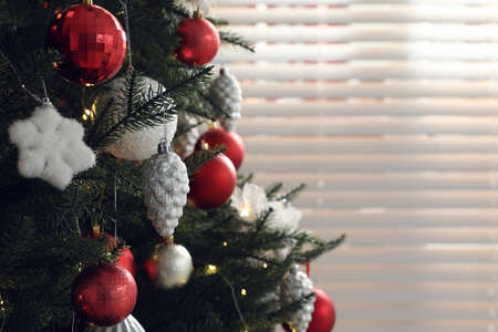 Beautifully decorated Christmas tree near window indoors, closeup. Space for textの写真素材