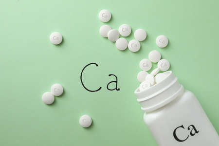 Flat lay composition with calcium supplement pills on light green backgroundの写真素材