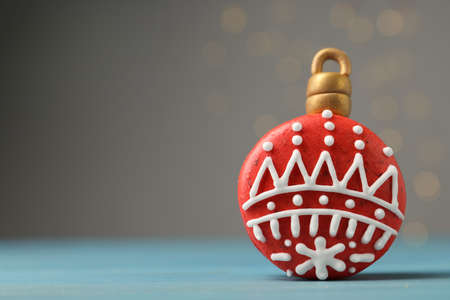 Beautifully decorated Christmas macaron on light blue wooden table against blurred festive lights, space for textの写真素材